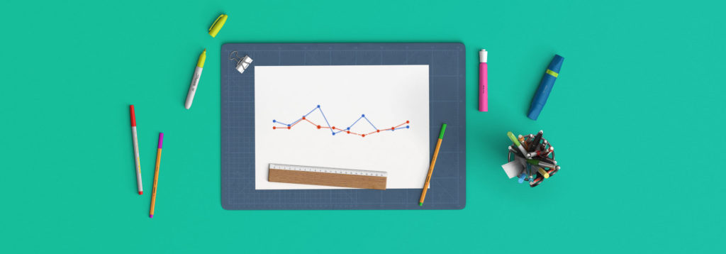 Flat lay of various writing utensils scattered and in a holder, a grid, and a sheet of paper with line projections on it